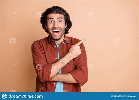 Photo Of Excited Young Guy Indicate Finger Empty Space Open Mouth Wear Brown T Shirt Isolated