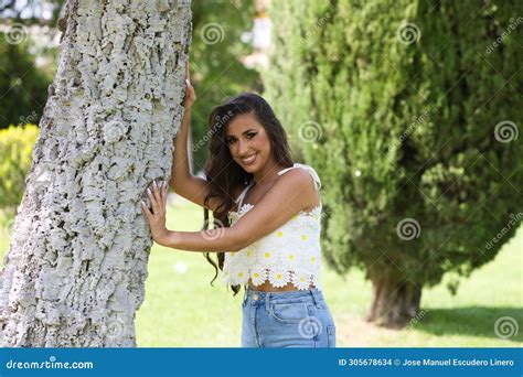 Beautiful Spanish Brunette Woman With Long Curly Hair And Big Slit Eyes Rests Her Hands On The