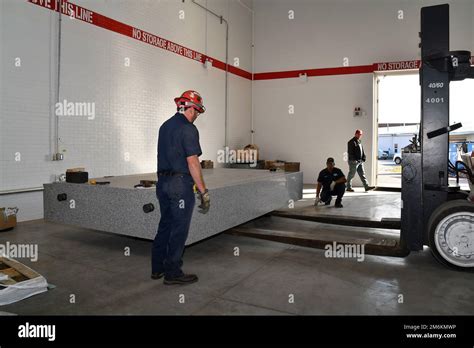 Los técnicos de aparejos mueven una mesa de granito que pesa 14