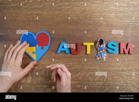 Autistic Boy Hands Holding Heart Shapeed Puzzle With Word Autism And