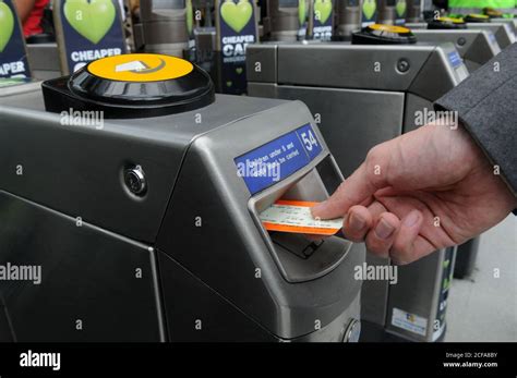 Hand Putting Train Ticket Into A Tfl Stations Ticket Barrier In Greater