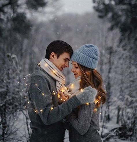 A Man And Woman Are Standing In The Snow With Lights On Their Hands