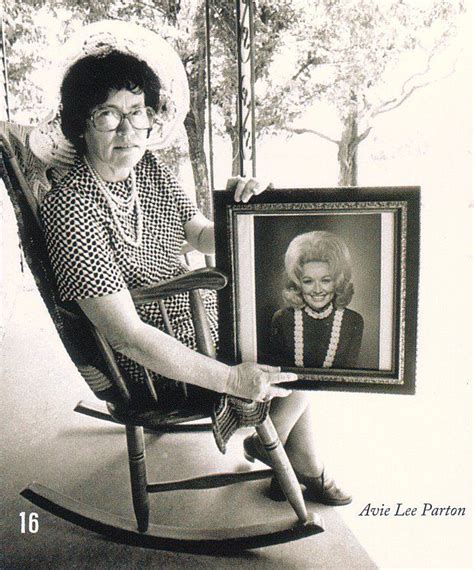 an older woman sitting in a rocking chair holding up a framed ...