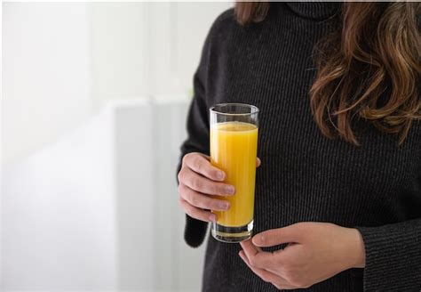 Premium Photo A Woman Holds A Glass Of Freshly Squeezed Orange Juice