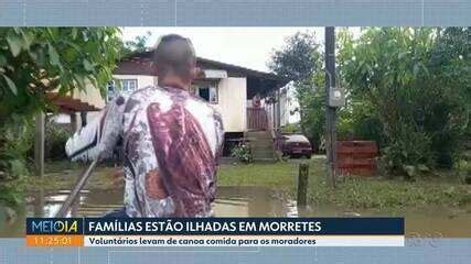 Voluntários levam comida de canoa para moradores ilhados por enchentes