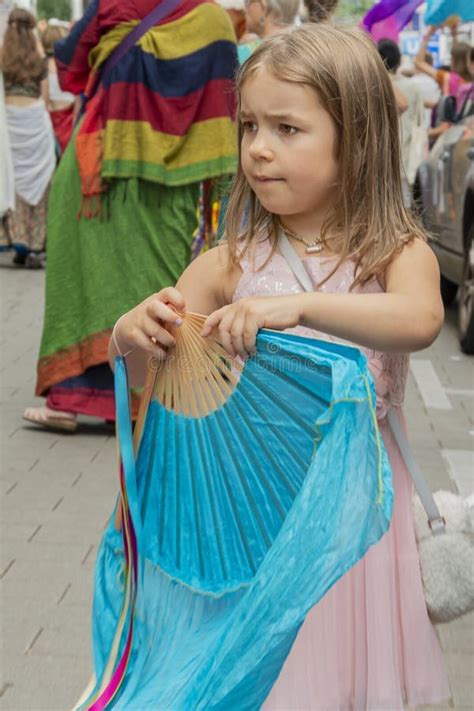 Portrait Of A Happy Blonde Girl On The Background Of Wooden Piles Of A Marine Berth For Ships