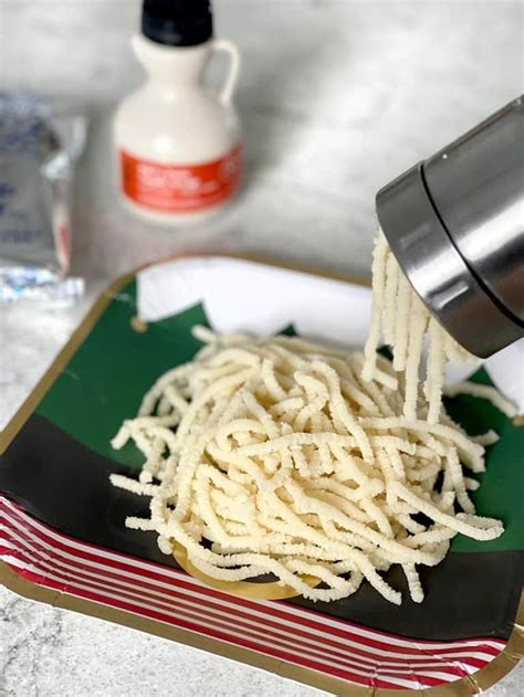 someone is pouring sauce over some noodles on a green and white plate with red striped napkins