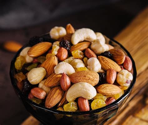 Recipiente con frutos secos orgánicos mixtos sobre tabla de madera