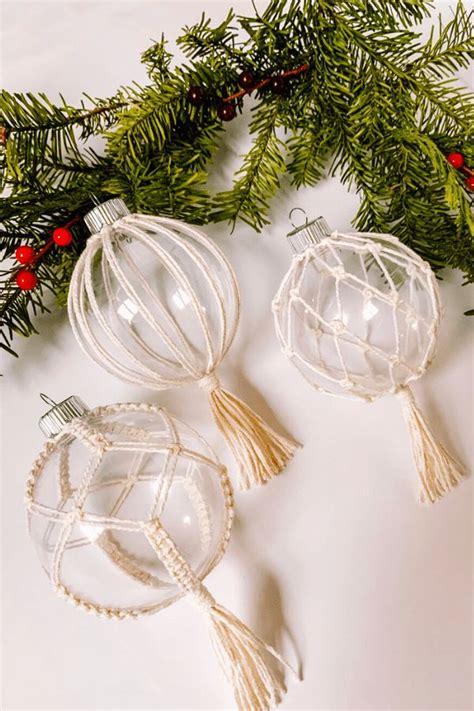 Two Glass Ornaments Are Sitting On A Table Next To Christmas Greenery