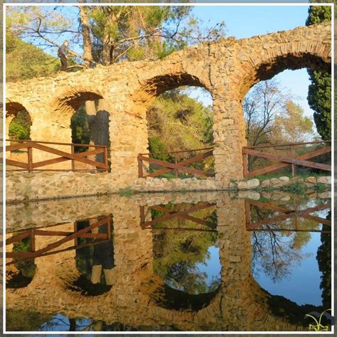 An Old Stone Bridge Reflecting In The Water