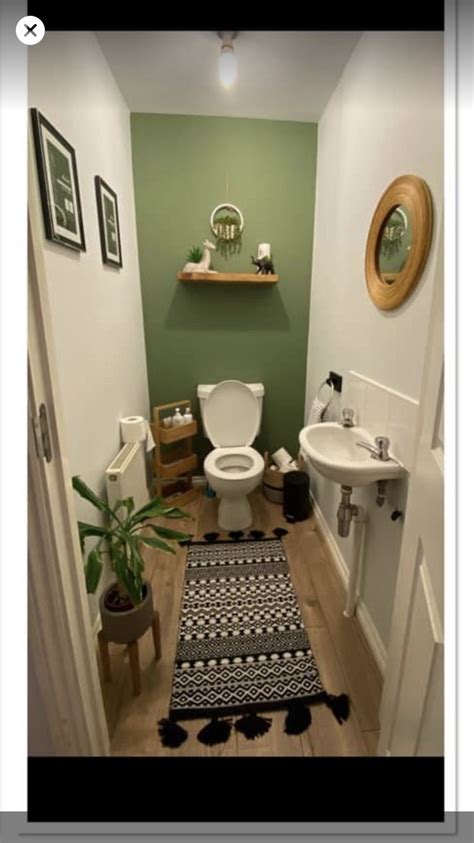 A Small Bathroom With Green Walls And White Fixtures Including A Rug