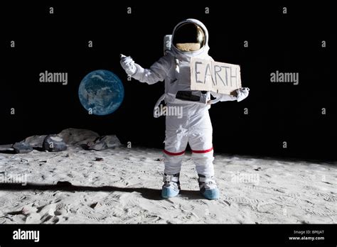 An Astronaut On The Moon With His Thumb Out Holding Earth Sign Stock