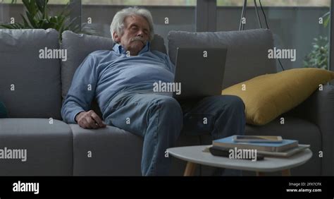 Elderly Man Falling Asleep On The Couch While Watching Videos On His