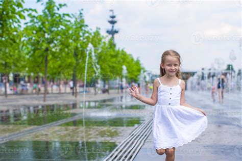 Little girl playing on a water fountain 20472815 Stock Photo at Vecteezy