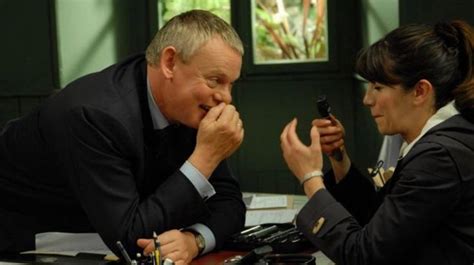 A Man And Woman Sitting At A Table With Cell Phones