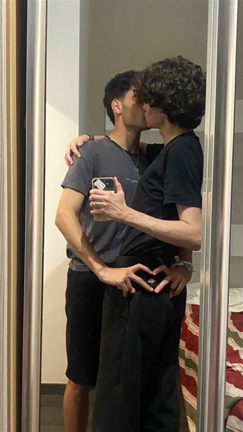 Two People Kissing Each Other In Front Of A Mirror With Their Arms