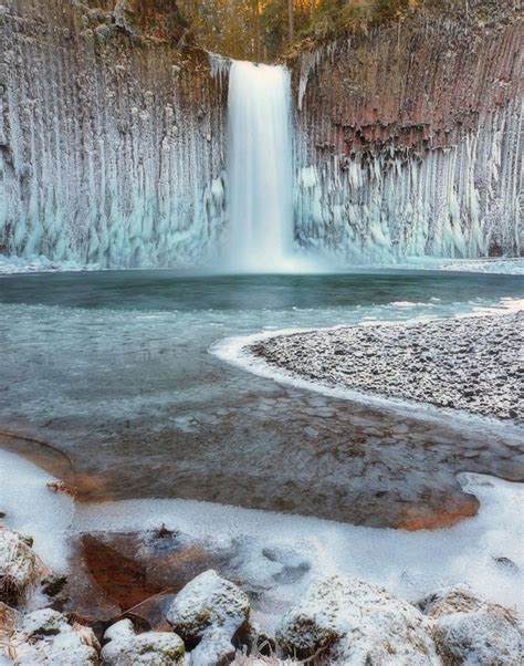 a waterfall with ice on the water and snow on the rocks in front of it