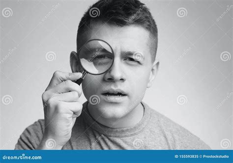 Young Suspicious Man Looking At Camera Through Magnifier Stock Image