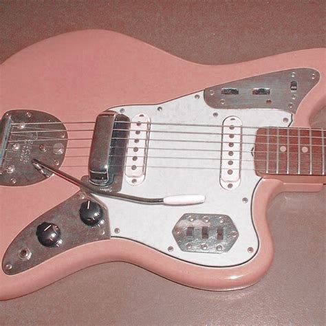 A Pink Electric Guitar Sitting On Top Of A Table