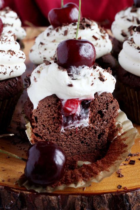 Chocolate Cupcakes With Cherries And Whipped Cream Frosting On A Wooden