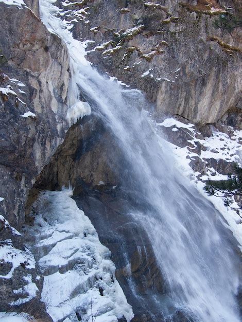 Premium Photo | A waterfall in the mountains with snow on the ground