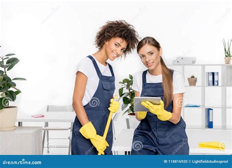 Beautiful Young Female Cleaners With Mop And Digital Tablet Smiling