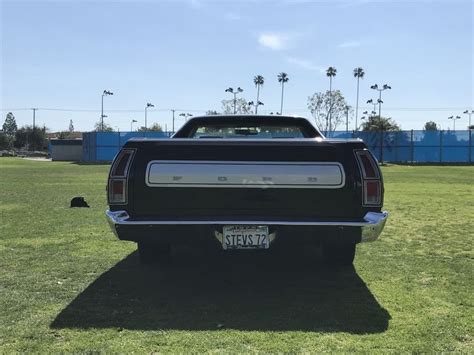 The Back End Of A Black Pickup Truck Parked In A Grassy Area With Palm