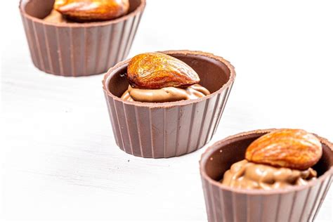 Three Chocolates With Whole Almonds On White Wooden Background Flip