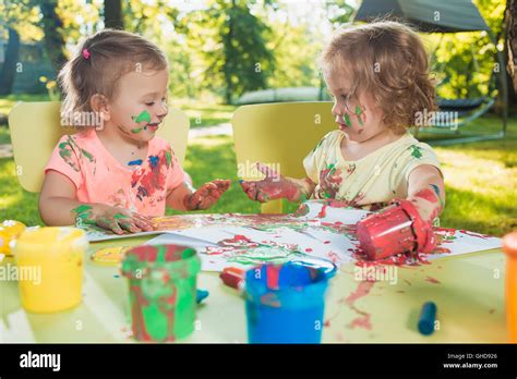 Two Year Old Girls Painting With Poster Paintings Together Against