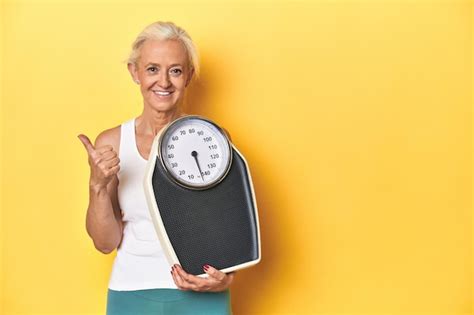 Mujer caucásica deportiva de mediana edad sosteniendo una balanza