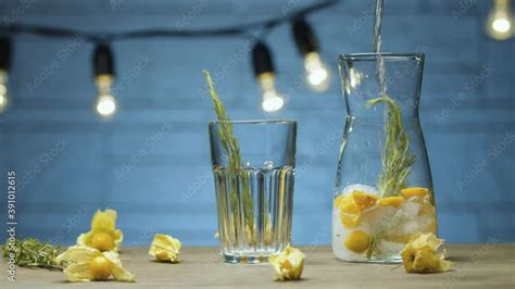 Close Up Sparkling Water Pouring Into The Glass Jug With Rosemary And