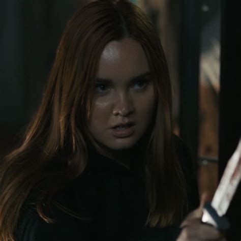 A Woman With Long Red Hair Holding A Knife In Her Hand And Looking At