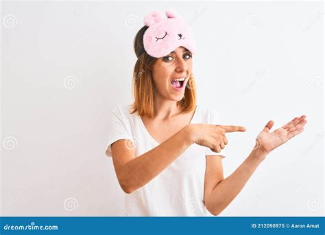 Beautiful Redhead Woman Wearing Sleeping Mask Over Background Amazed