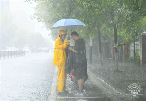 【吉网图集】长春突降大雨 外卖小哥雨中相互帮忙换雨衣 中国吉林网