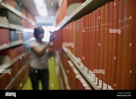 Bookshelves In A Library In Front Of A Young Woman Reaching For A Book