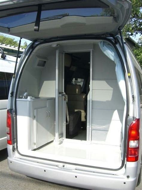 The Back End Of A White Van With Its Doors Open