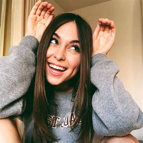 A Woman Sitting On The Floor With Her Hands Behind Her Head And Smiling