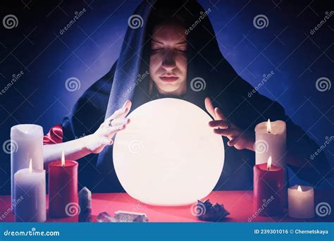 Soothsayer Using Glowing Crystal Ball To Predict Future At Table In