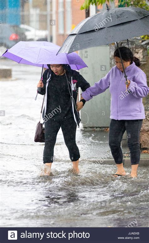 Two Woman Walking Through Flash Flooding Water On Their Way Home After