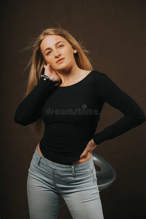 Vertical Shot Of An Attractive Blonde Female Posing While Sitting On A