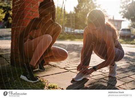 Multiethnische Sportlerinnen wärmen sich auf dem Gehweg im Stadtpark