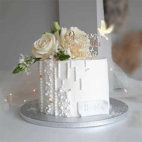 A White Wedding Cake Decorated With Pearls And Flowers