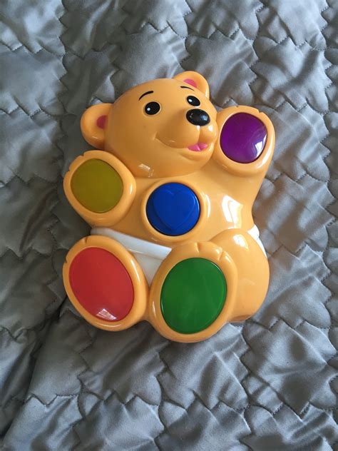 a toy bear sitting on top of a bed covered in white sheets and colorful buttons