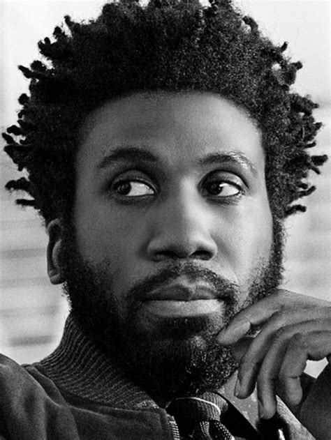 A Black And White Photo Of A Man With Dreadlocks Looking At The Camera