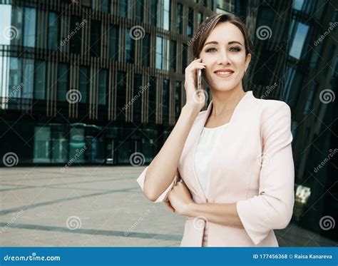 Beautiful Young Business Woman Uses A Mobile Phone In Front Of A Modern