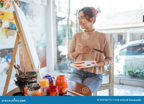 Asian Female Painter Painting On Canvas In Her Workshop Stock Image