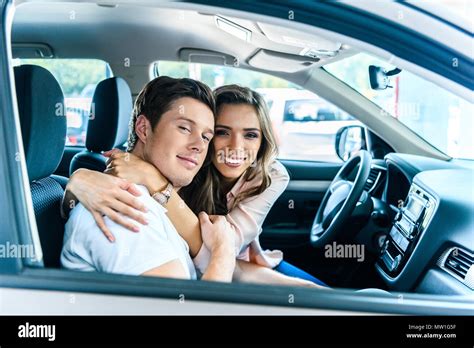 Happy Heterosexual Couple Sitting In A Car Salon Hugging And Smiling