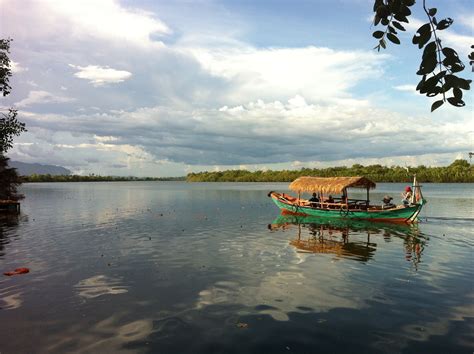 Beautiful View Of Kampot River With A Passing Fishing Mens Boat