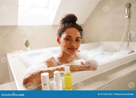 Woman Happily Bathing In Foamfilled Bathtub In Rectangular Bathroom