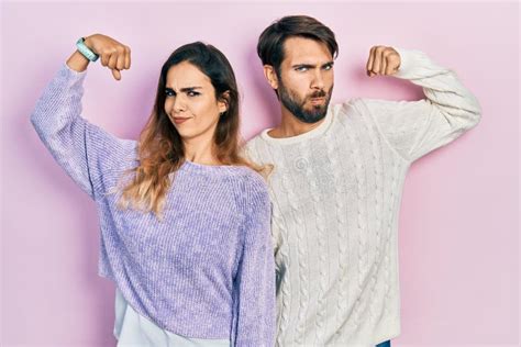 Young Hispanic Couple Wearing Casual Clothes Showing Arms Muscles